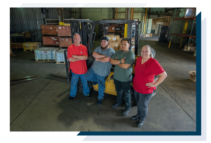 4 employees by a forklift